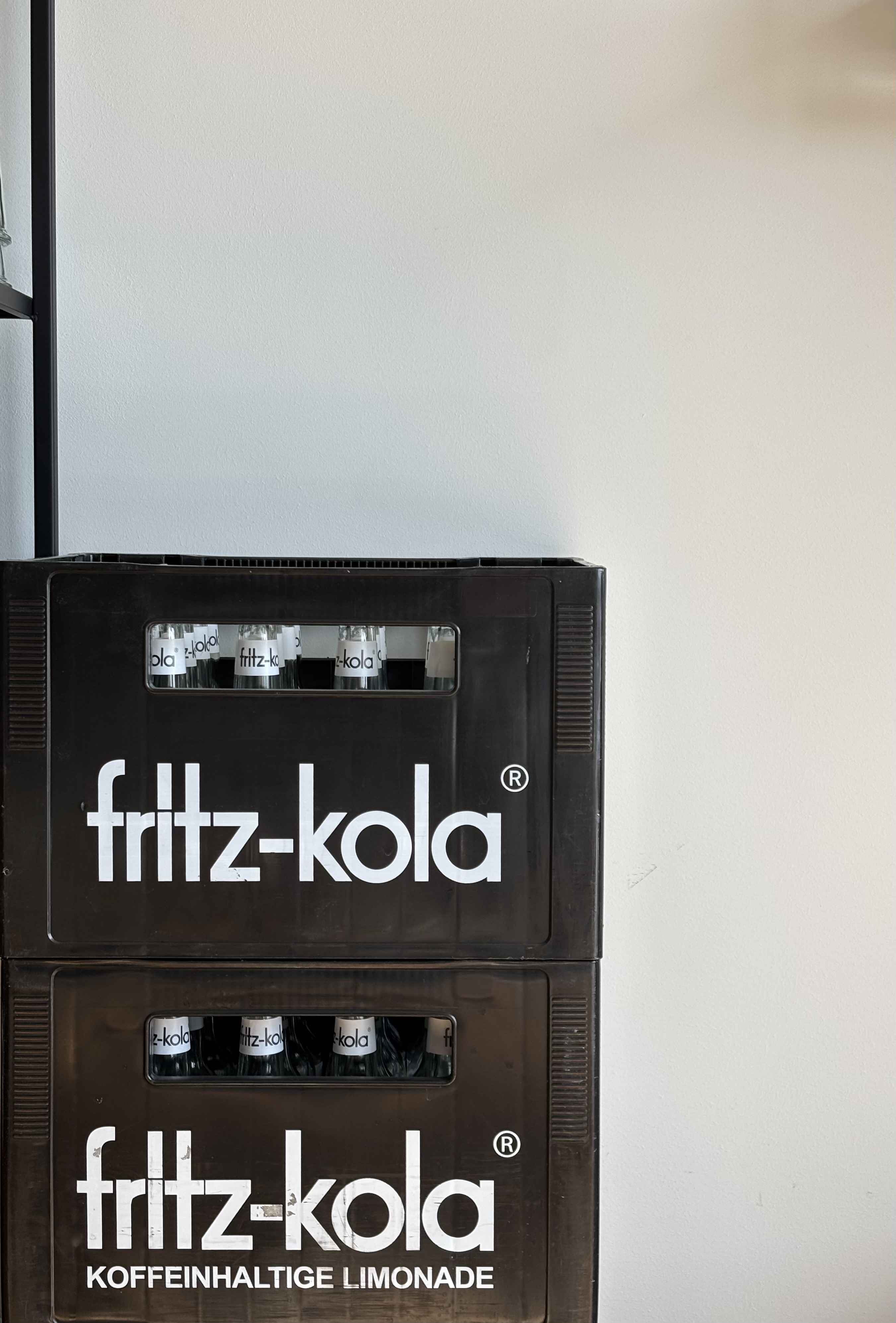 Henning’s original typeface, still in use by fritz-kola, displayed in white text on two black crates stacked on top of each other.