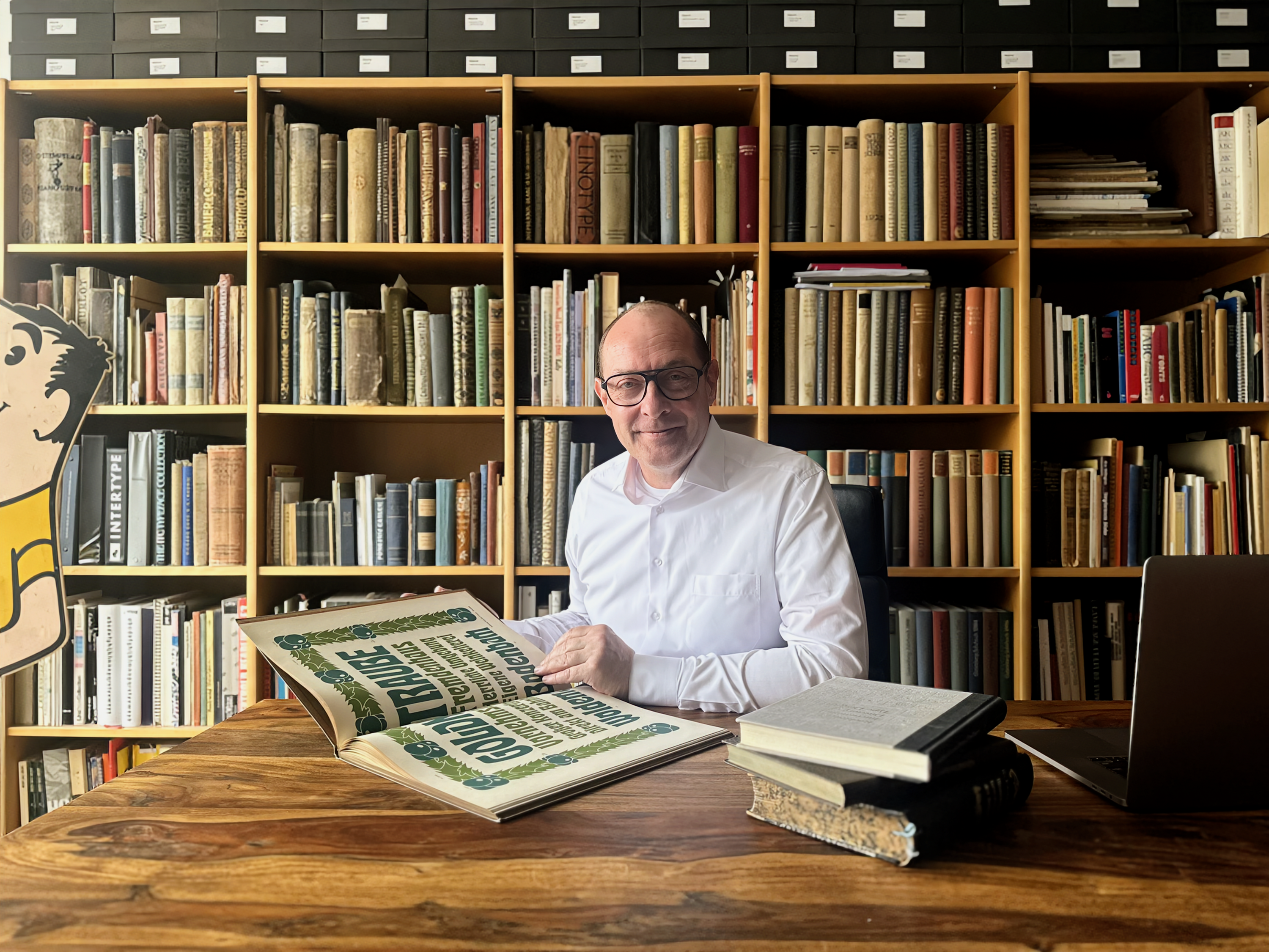 Henning Krause portrait with his library. Bookshelves fill the background. 