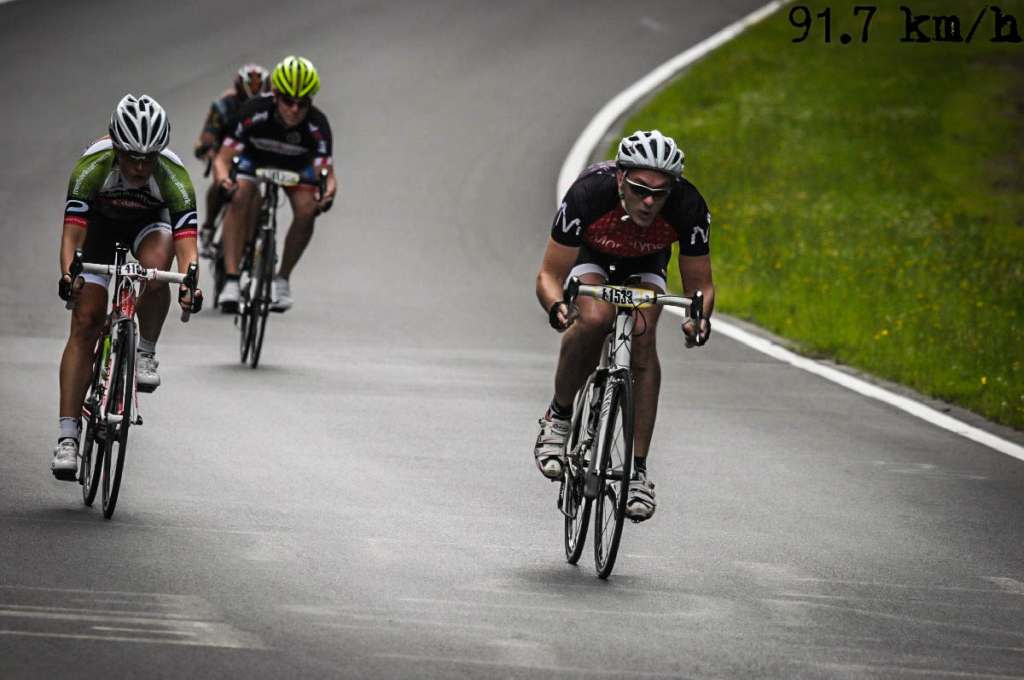 Three bicyclists in a race. Henning is in the Monotype jersey on the right, traveling at 94 km per hour.