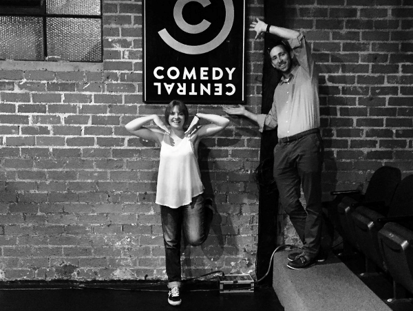 Black and white photo of Bill (right) and his comedy partner, Erin Berry (left) in front of a brick wall and the Comedy Central logo at the Comedy Central Theater in Hollywood.