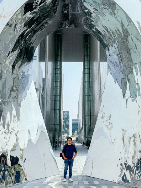 Marco of Hanken Design Co. at the Dubai Design District, standing under a shiny, textured mirrored arch.