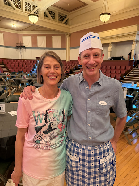 Jan and Caroline posing before their Broadway performance with the Polymnia Choral Society. Jan is dressed as waitress “Janet” — not a waiter — to stay true to the musical’s title.