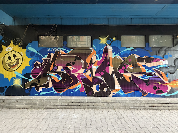 Colorful graffiti street art of a smiling yellow sun and letters in Bulgaria.
