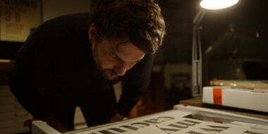 A still image from Foundry Stories showing Rene Bieder in his studio looking at type.
