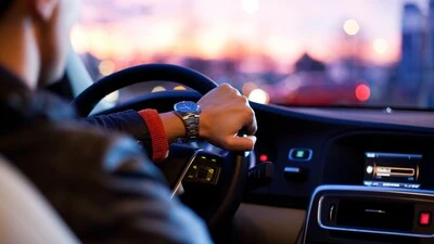A man is shown driving a car as if the viewer is in the back seat.