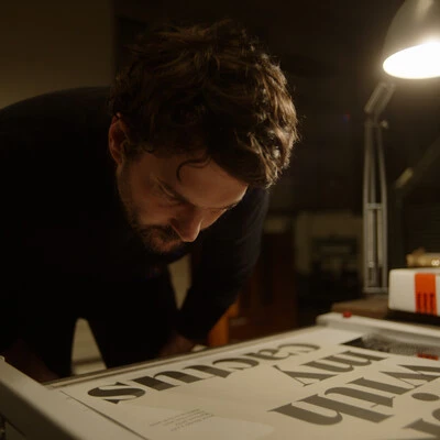 A still image from Foundry Stories showing Rene Bieder in his studio looking at type.