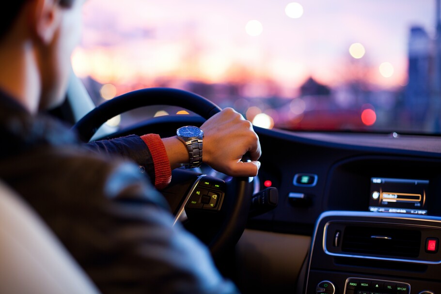 Man driving a car A man is shown driving a car as if the viewer is in the back seat.