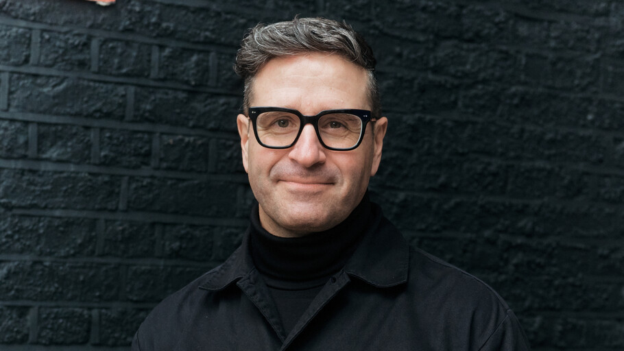 Portrait of Charles Nix wearing a black shirt in front of a black brick background cropped 16x9.