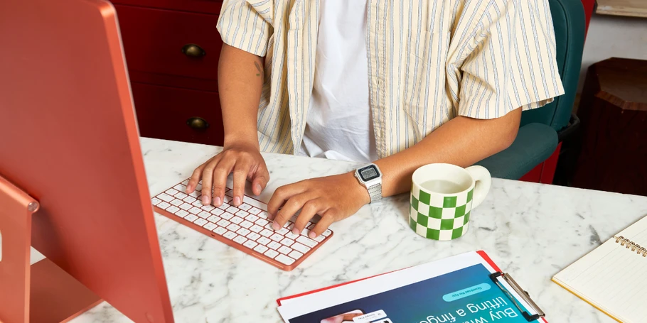 Person working on computer with tablet and coffee